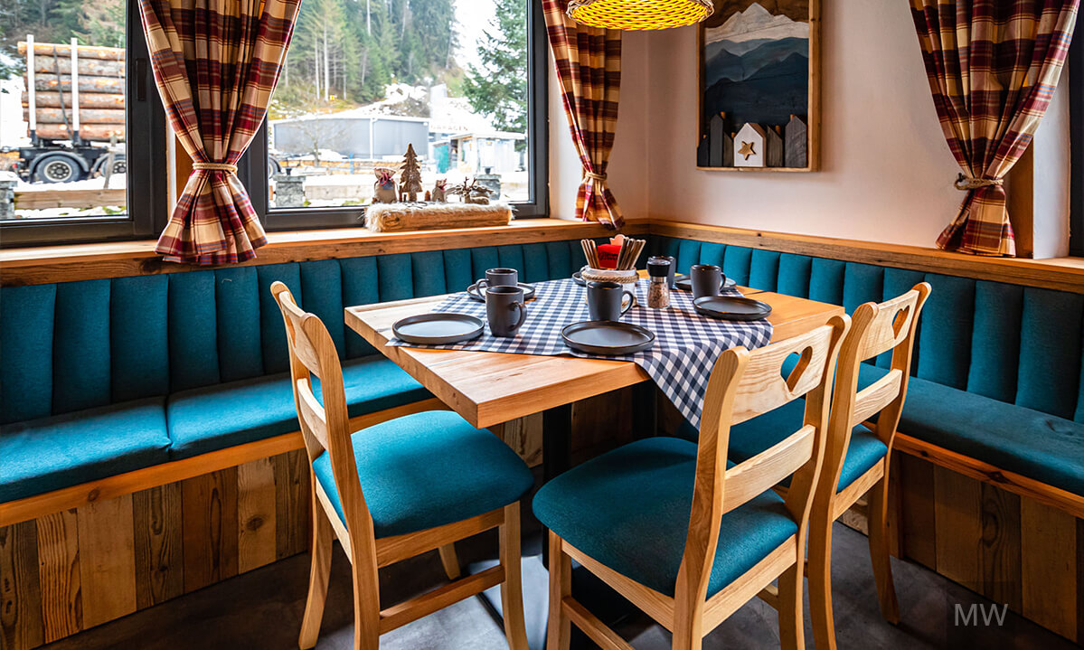 Colț de dining cozy cu masă din lemn și decor rustic. Colț de dining rustic cu masă din lemn și scaune cu tapițerie albastră.