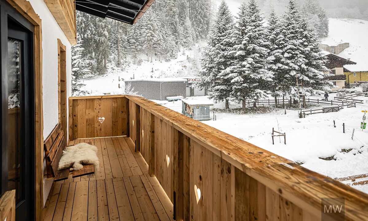 Balcon rustic cu vedere la pădurea înzăpezită. Balcon cozy din lemn cu vedere la peisajul înzăpezit. kitzbuchel