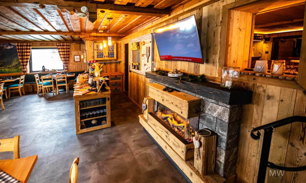 Restaurant cozy cu atmosferă de cabană și decor rustic. Restaurant rustic cu grinzi din lemn și semineu.