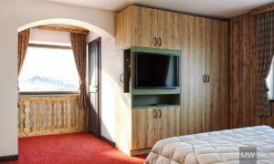 kitzbuhel most wanted design 3d rendering, room 001, old wood wall, built in dressing and storage space, tv mounted on it, greed accesnt in furniture Vizualizare 3D și design interior realizat de Most Wanted Design Cluj. Perete din lemn vechi, spații de depozitare și dressing integrate, televizor montat pe mobilă, accente verzi în mobilier.