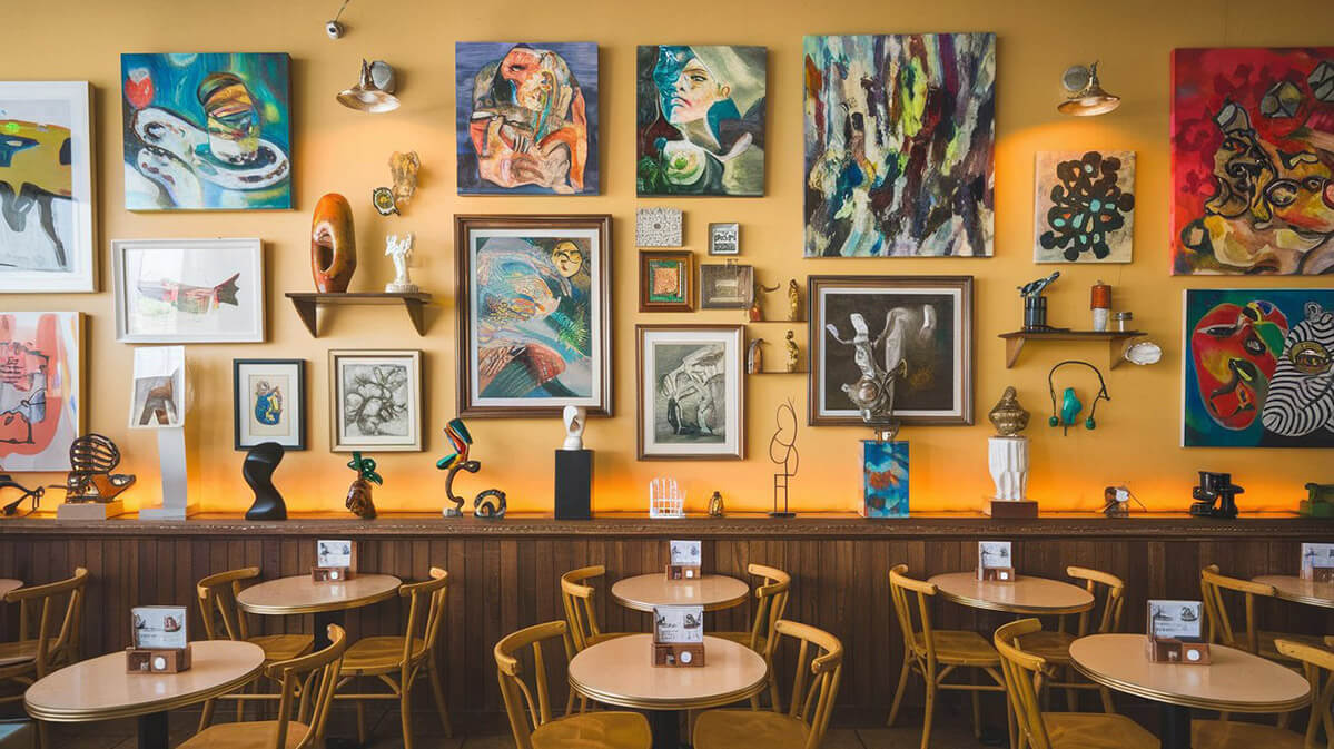 Cafenea artistică: locul unde cafeaua întâlnește creativitatea Interior vibrant de cafenea care servește și ca galerie de artă dinamică, cu lucrări ale artiștilor locali expuse pe pereți și pe piedestale.