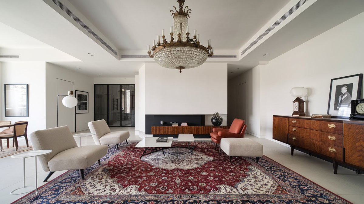 Stil modern cu accente nostalgice. O sufragerie modernă și elegantă, combinând elemente contemporane cu accente nostalgice. Un candelabru vintage din detalii fine atârnă de un tavan minimalist, iar mobilierul modern este în tonuri neutre, completat de un covor persan cu motive complexe în nuanțe de roșu și albastru. O comodă clasică din lemn, cu mâneri din alamă antică, adăpostește obiecte retro, precum un ceas vintage și fotografii alb-negru.