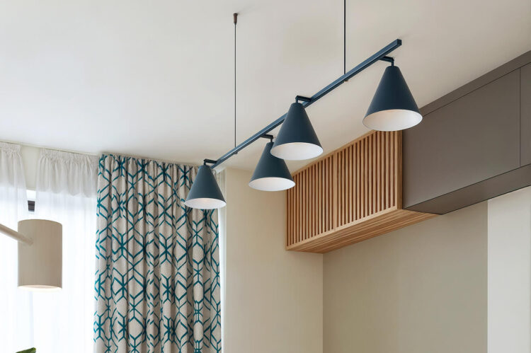 Interior elegant cu lampă suspendată albastră și perdea decorativă.