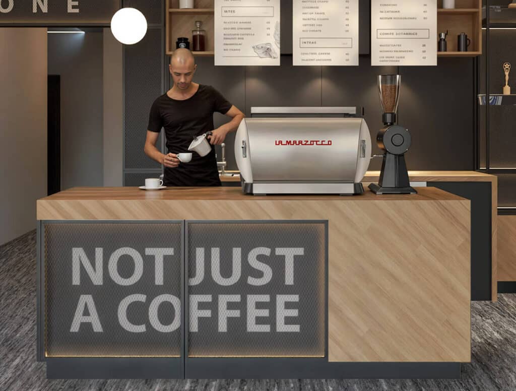 Barista pregătind cafea la un espressor La Marzocco cu mesajul „NOT JUST A COFFEE”.