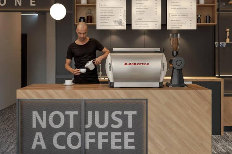 Barista pregătind cafea la un espressor La Marzocco cu mesajul „NOT JUST A COFFEE”.