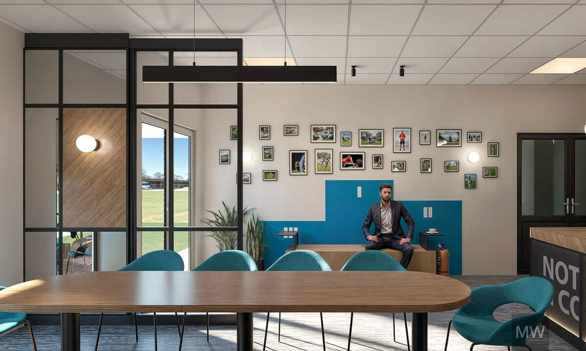 cafenea-sportiva-design-modern-decor-perete-targu mures Interior modern de cafenea sportivă cu perete din sticlă, masă din lemn și scaune albastre. Pereții sunt decorați cu tablouri înrămate, iar în fundal un bărbat în costum stă pe o bancă albastră.