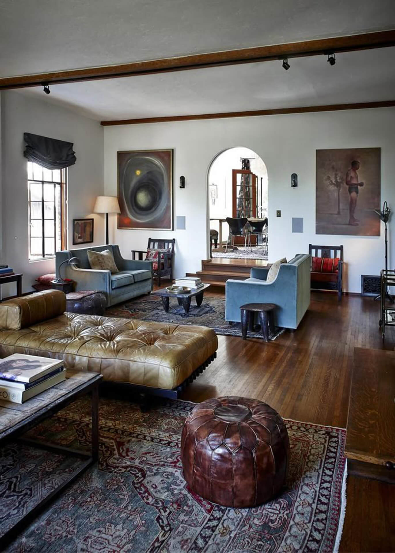 Warm living room with modern and traditional design elements Cozy living room with blue sofas, leather ottoman, wooden coffee table, and patterned rug.