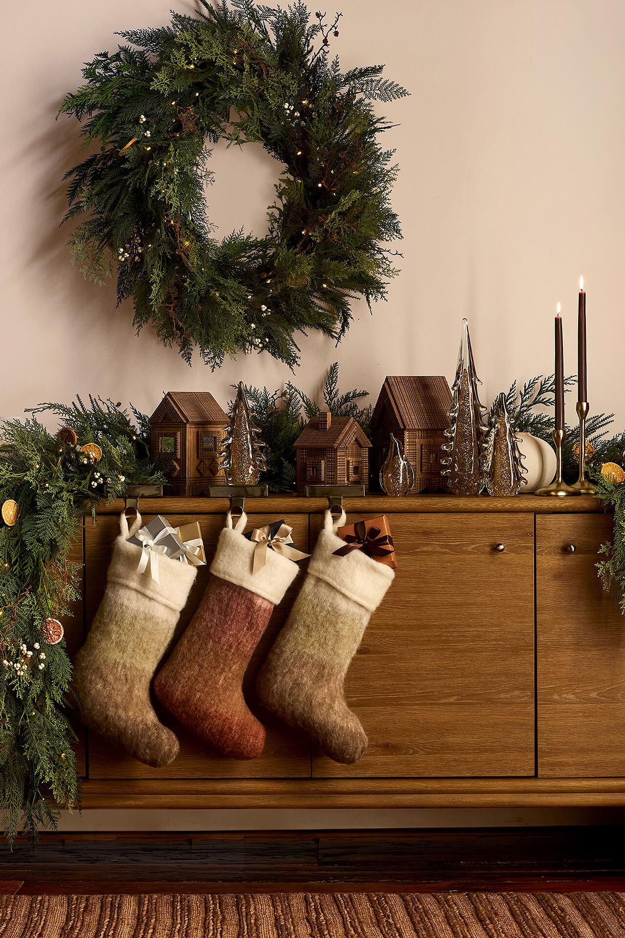 Christmas Sideboard Decor with Greenery, Stockings, and Candlelight Festive wooden sideboard with greenery, Christmas stockings, candles, and wreath