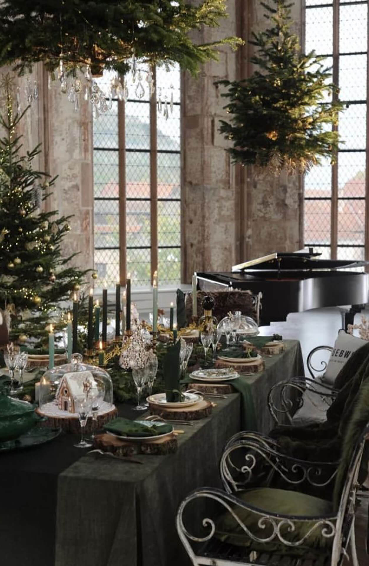 Elegant Christmas Table Setting with Greenery and Candlelight Elegant Christmas table with green tablecloth, candles, greenery, and chandeliers