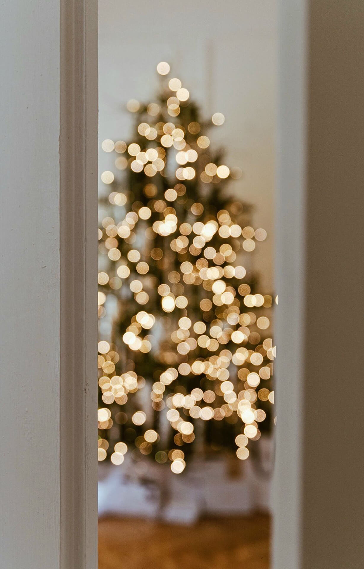 Festive Christmas Tree Through Doorway Christmas tree with twinkling lights viewed through a doorway