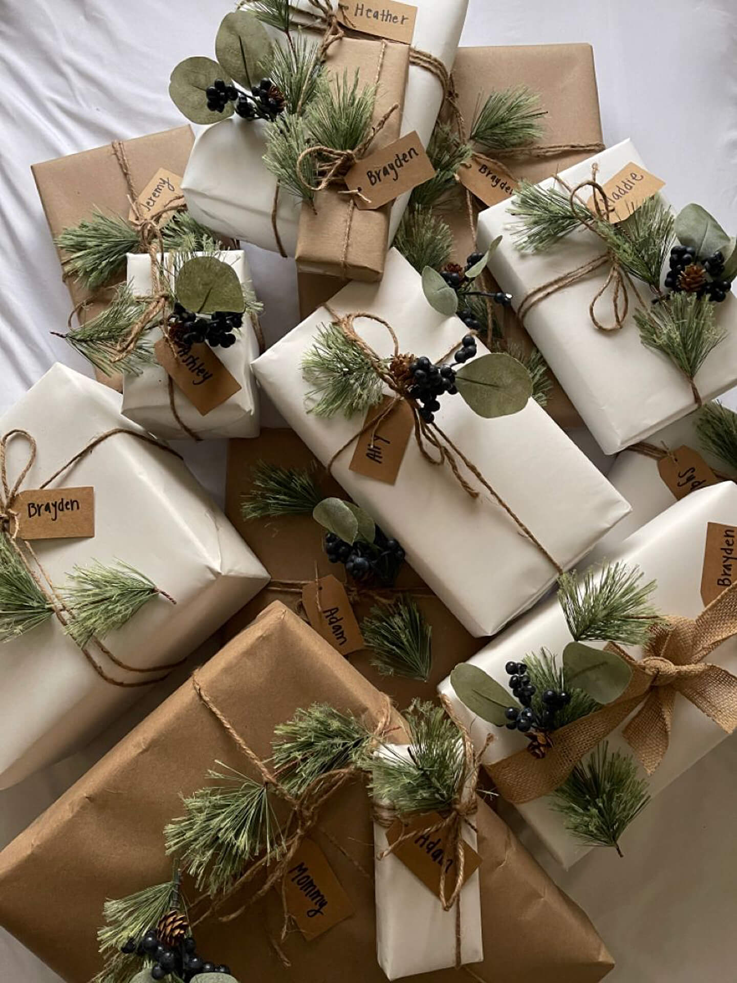 Rustic Christmas Presents with Personalized Tags Christmas presents wrapped in brown and white paper with pine branches and personalized tags